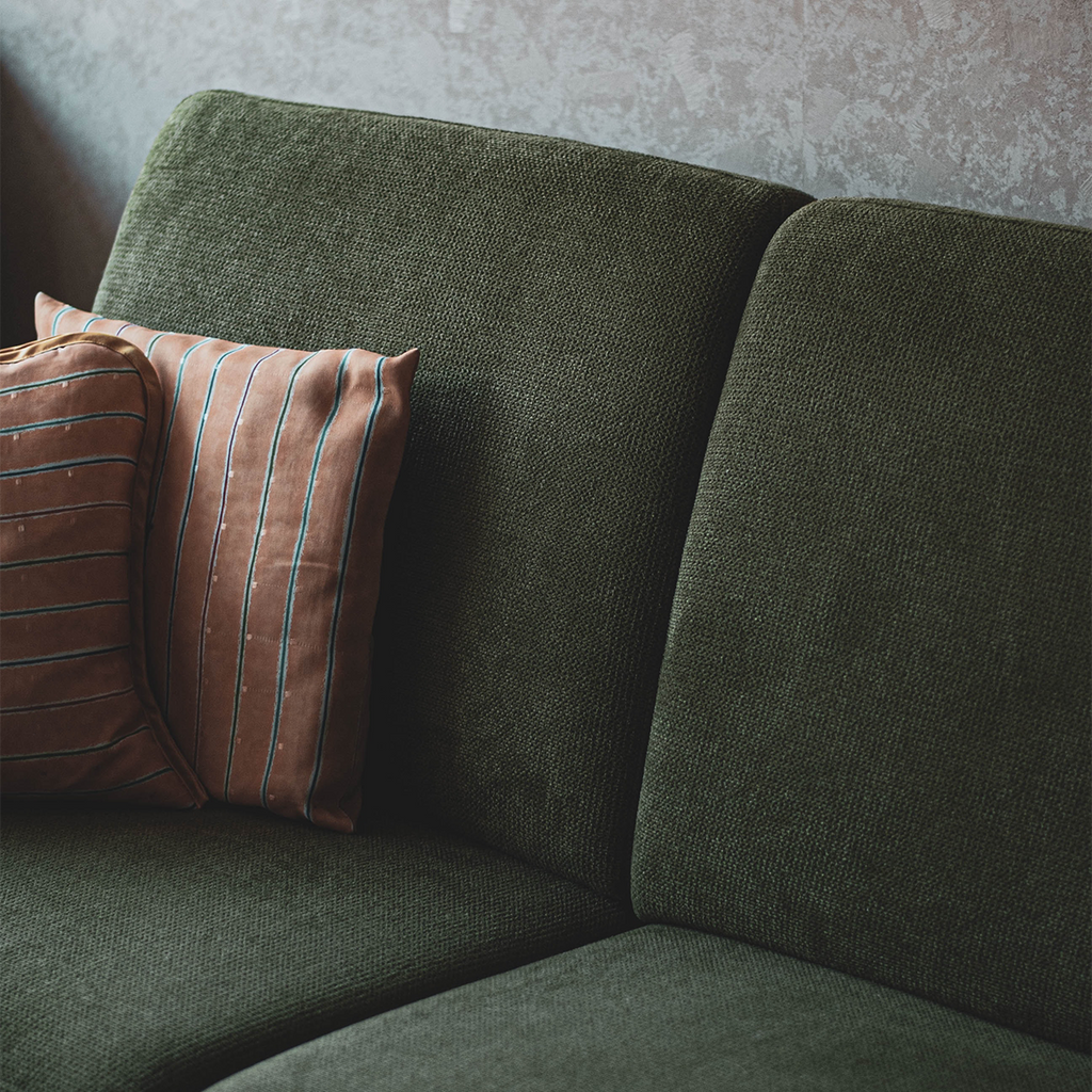 close up of a dark green couch cushion, with striped pink pillows